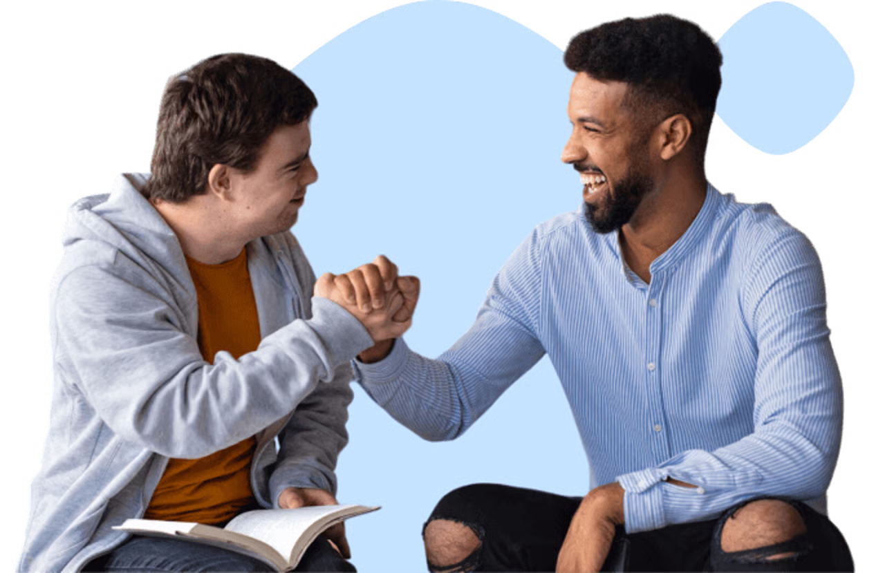 Two men smiling and fist bumping, one holding an open book.